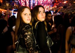 Due ragazze in posa sotto le luci rosse a pioggia