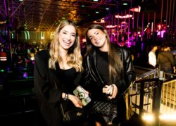 Due amiche sorridono con lo smartphone in mano sulla balconata