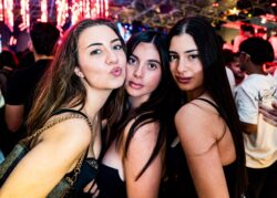 Tre amiche in posa sotto le luci rosse del locale